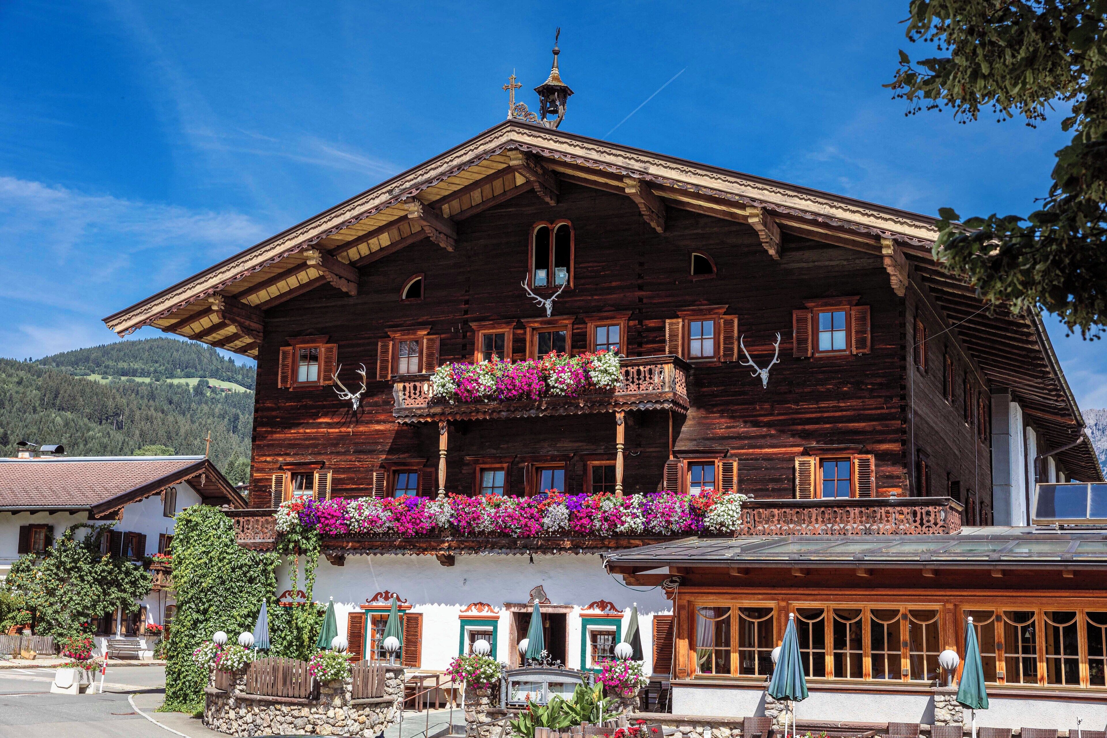 Ein traditionelles Holzhaus mit Balkonen, Blumenkästen und einer Glocke.