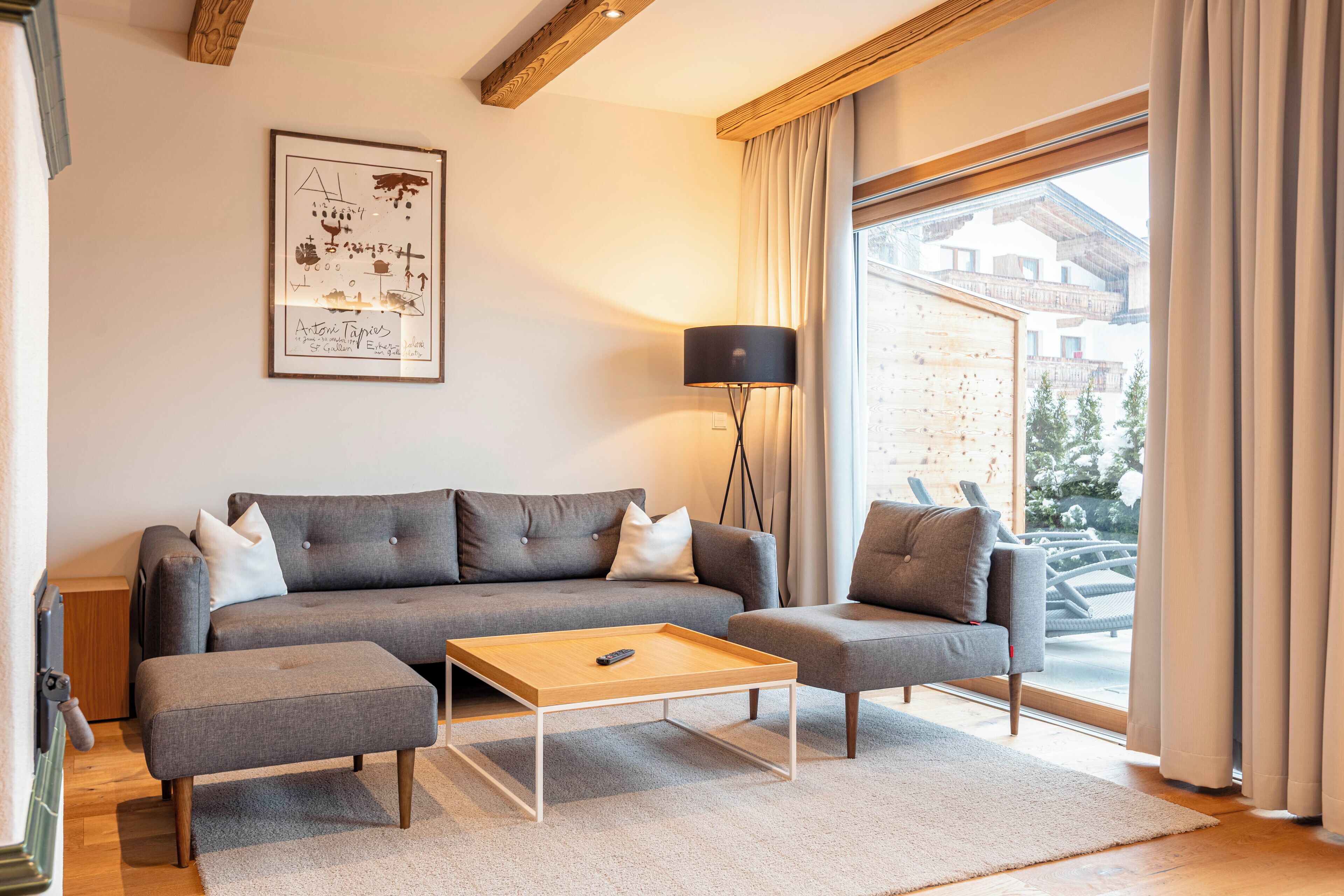 Una sala de estar moderna con un sofá gris, una mesa de centro de madera y una lámpara de pie.