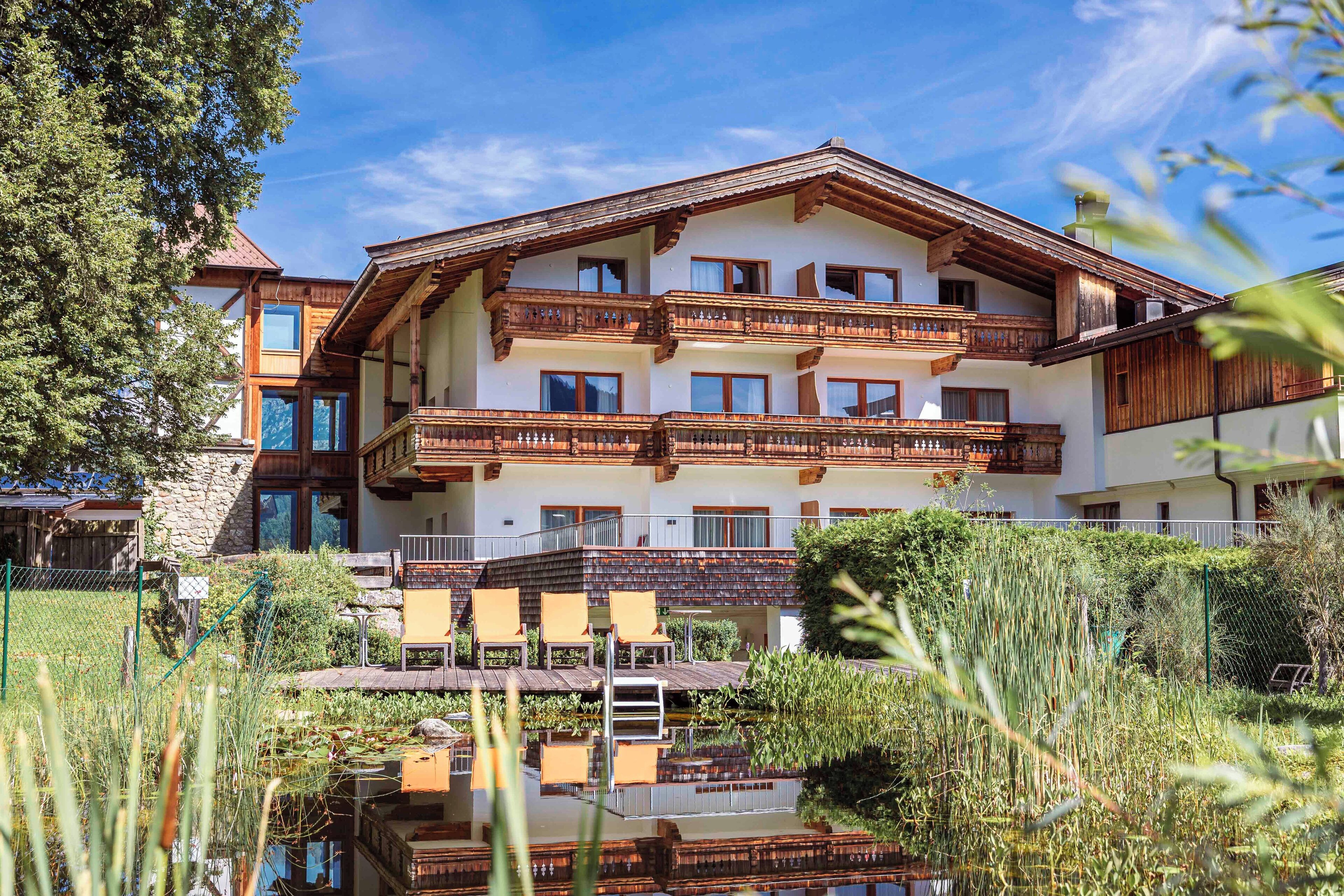 Un hotel de varios pisos con balcones, piscina y vegetación circundante.