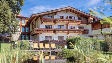 Un hotel de varios pisos con balcones, piscina y vegetación circundante.