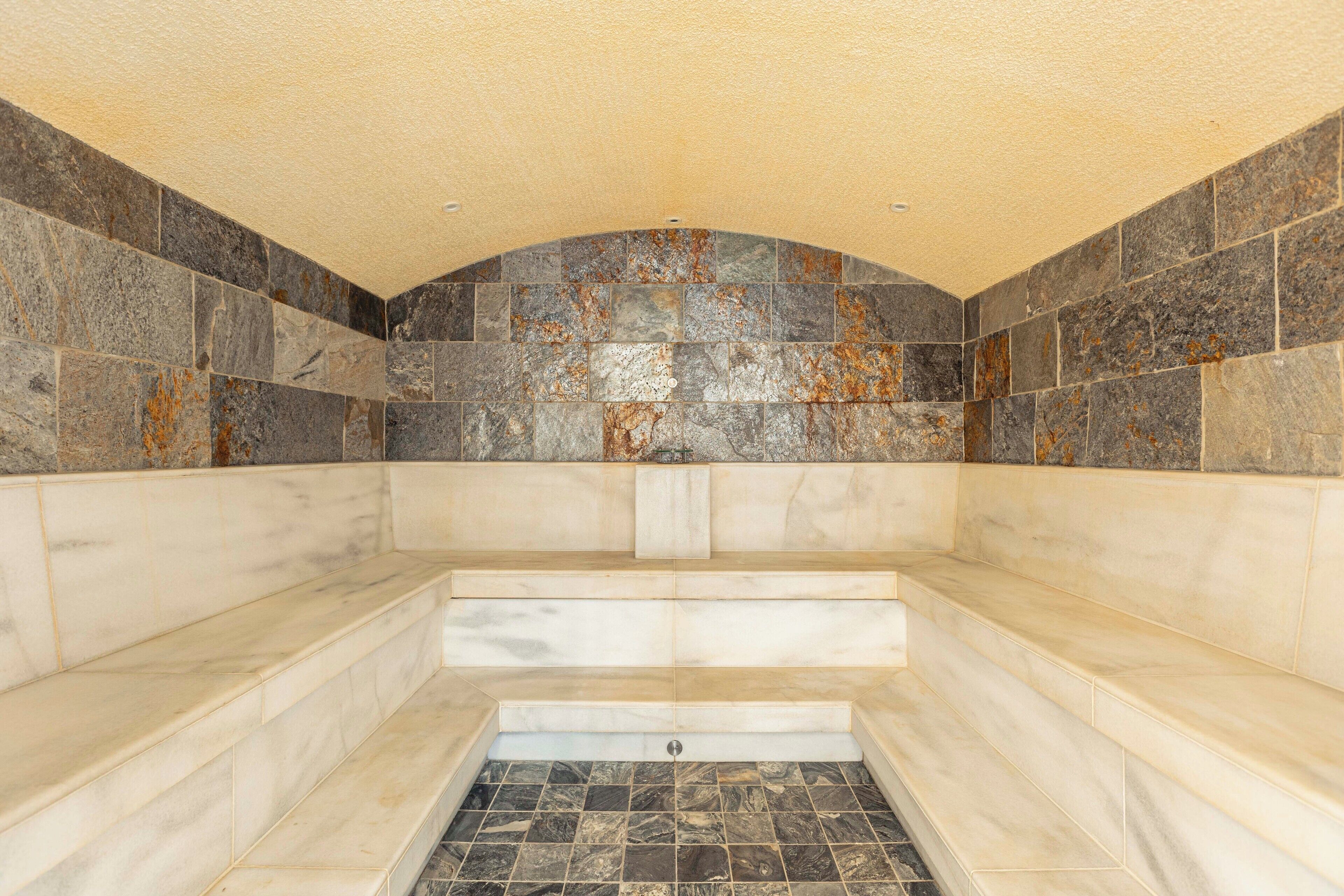 A bathroom with a freestanding bathtub, tiled walls, and a marble floor.