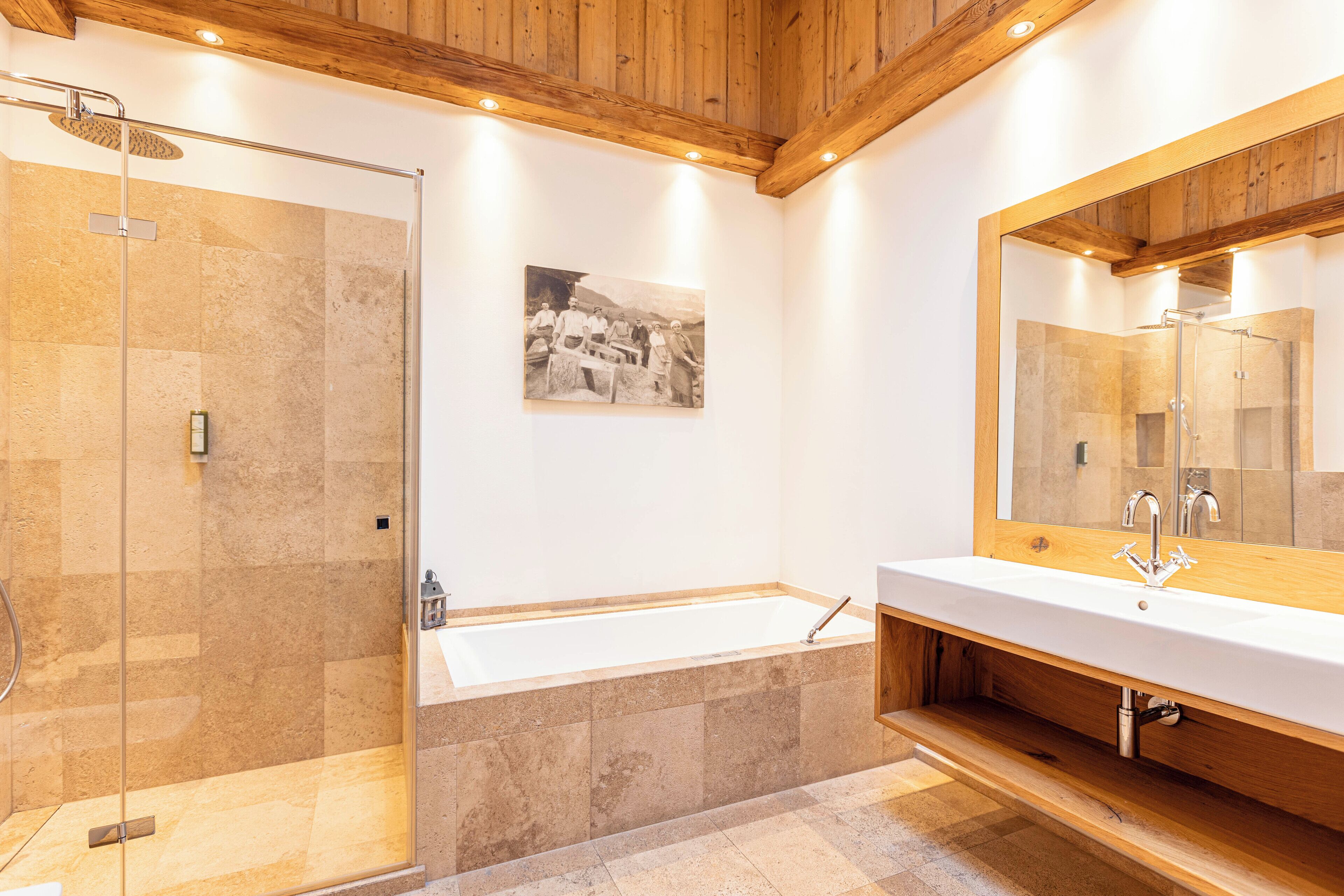 A modern bathroom with a glass-enclosed shower, a large bathtub, and a wooden vanity with a mirror.