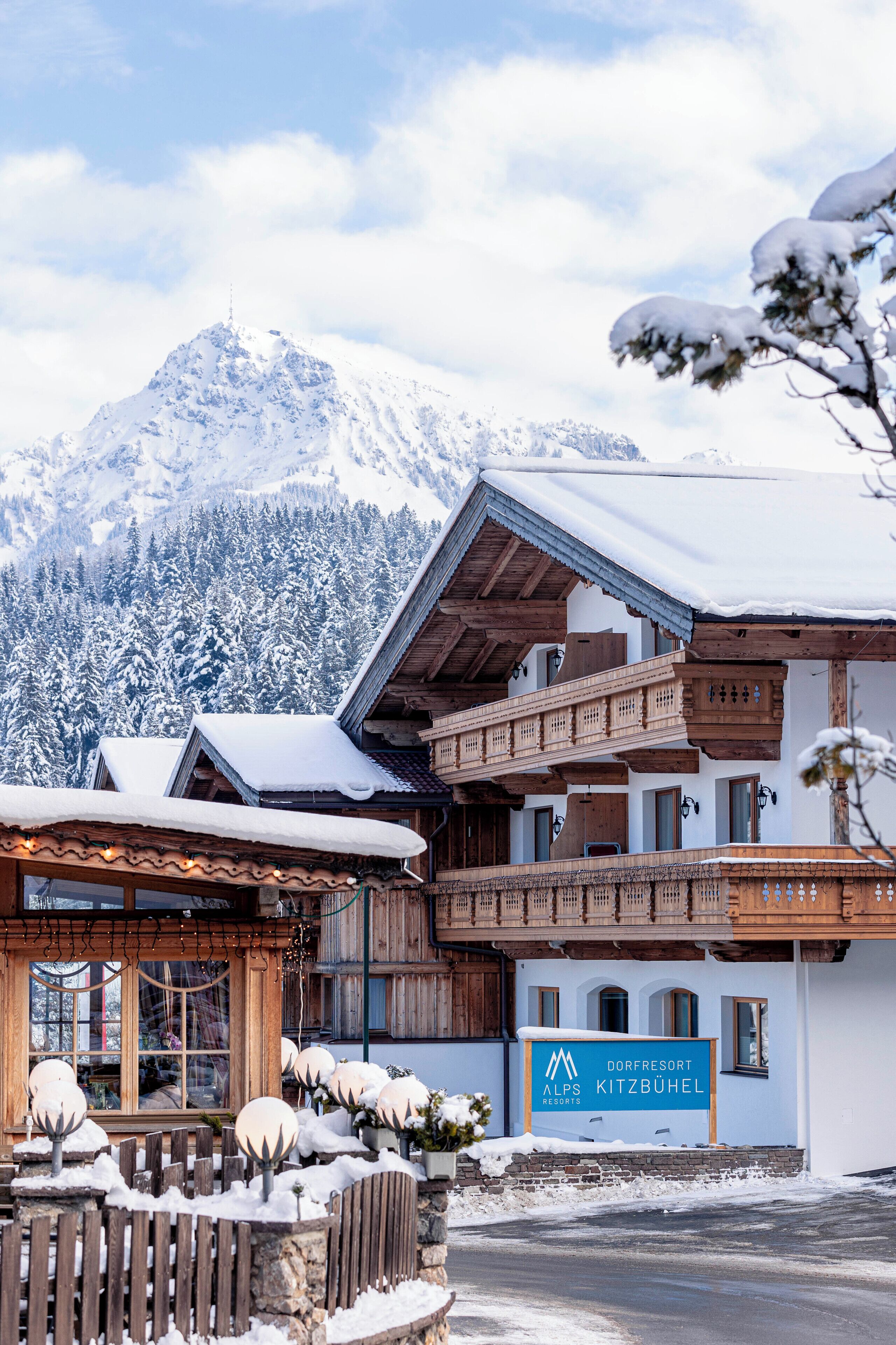 Un tipico edificio di legno alpino con un'insegna che riporta 'Dorfresort Alps Kitzbühel'.