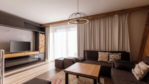 Un salon moderne avec un téléviseur à écran plat, une table basse en bois et un ensemble de canapés.