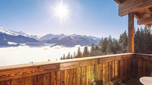 Eine Holzterrasse mit Blick auf schneebedeckte Berge und einen Wald.