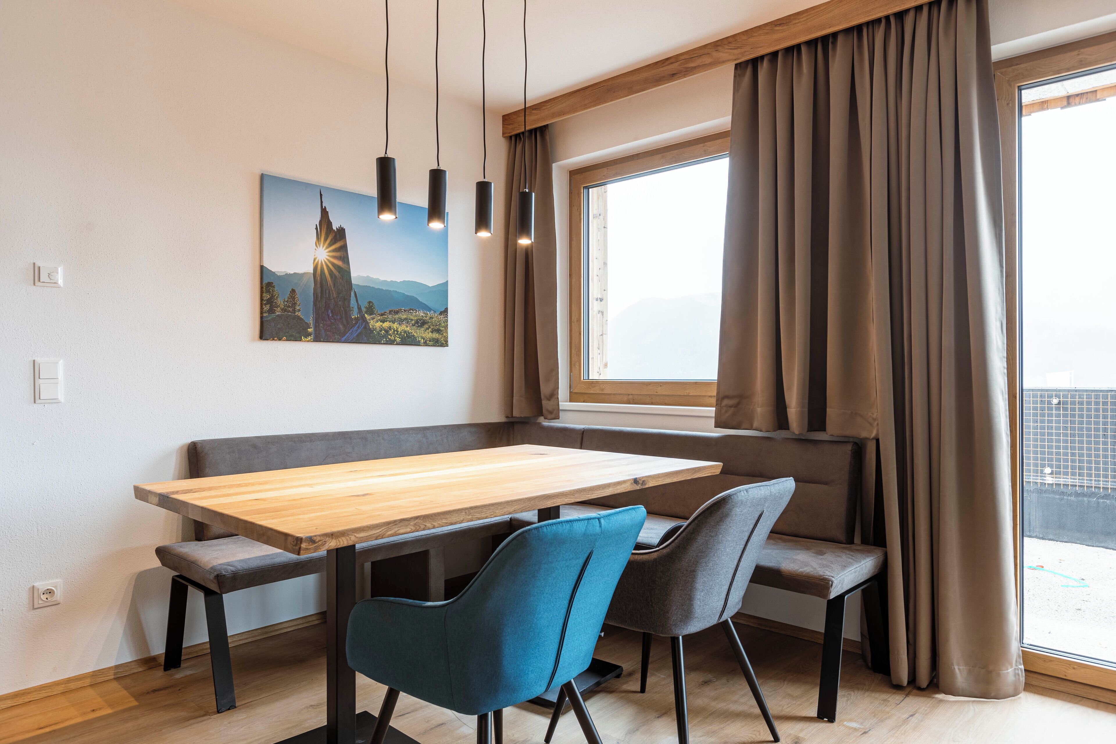 A modern dining area with a wooden table, blue and gray chairs, and a bench.