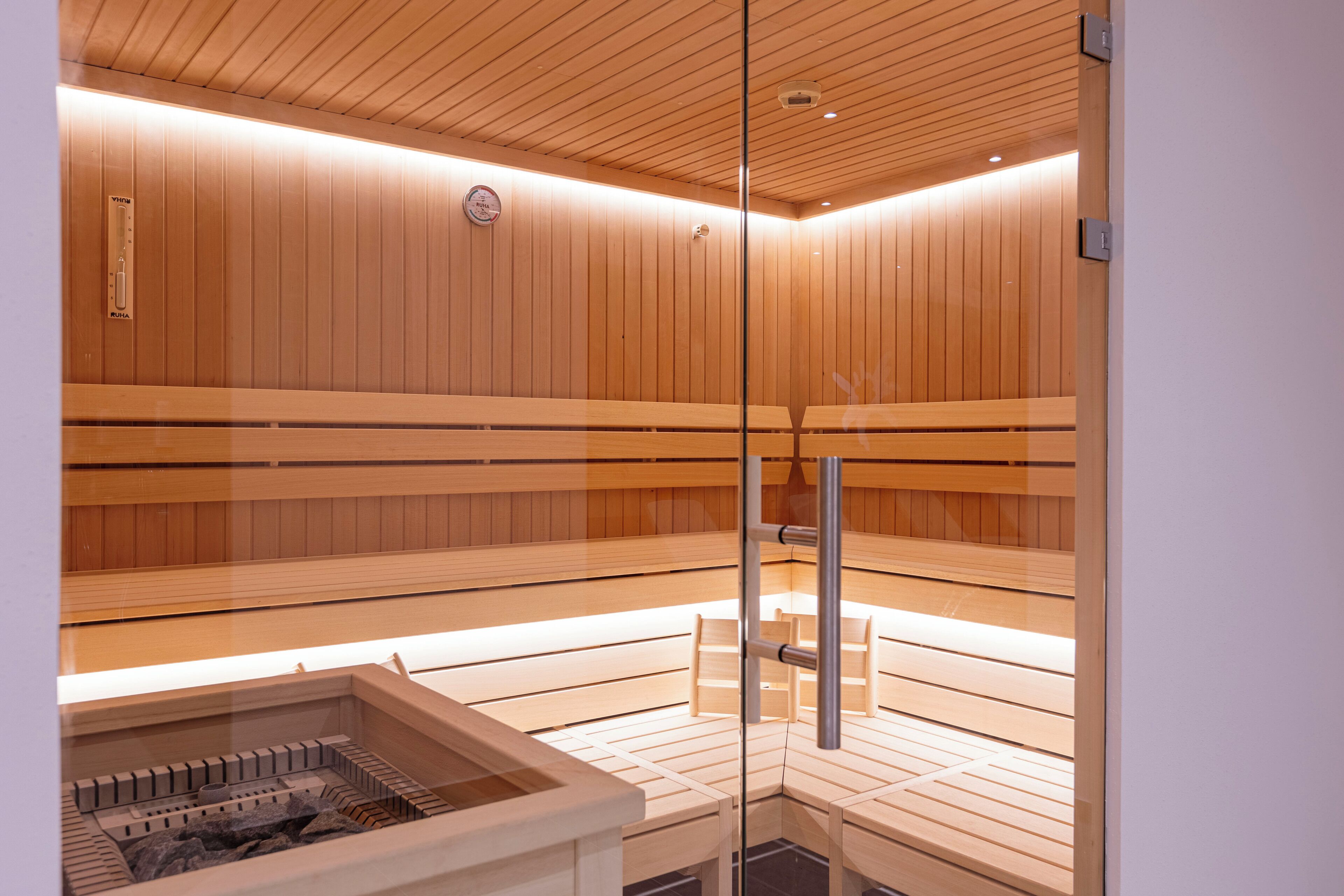 Eine Sauna mit Holzbänken und einer Glastrennwand.