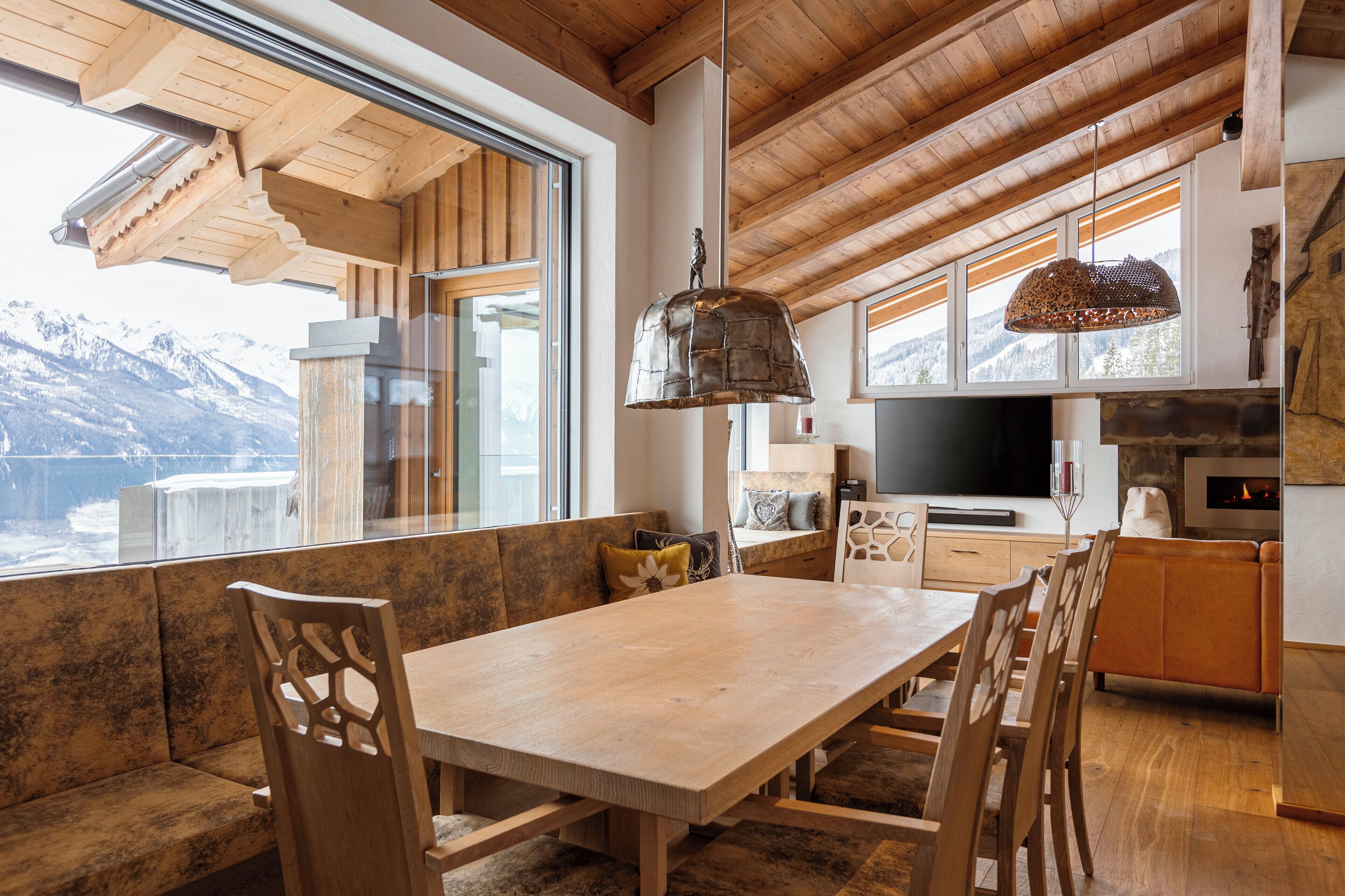 A modern kitchen with wooden beams, a large window, and a stone fireplace.