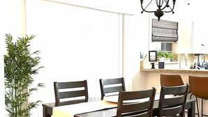 A dining area with a wooden table and chairs, a chandelier, and a potted plant. - Amistad House (Del Rio)
