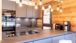 A modern kitchen with a built-in oven, a sink, and a coffee maker.