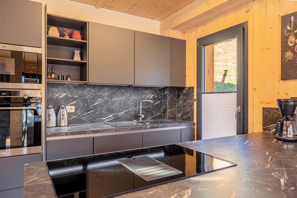 Una cocina moderna con estufa integrada, un lavabo y un salpicadero de mármol.