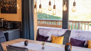 A dining area with a wooden table, chairs, and hanging light bulbs.