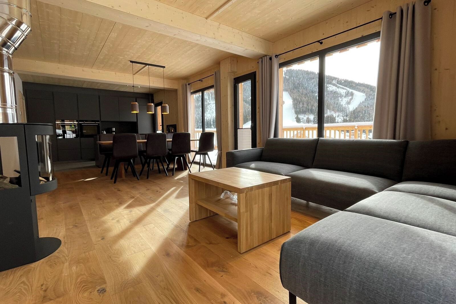 A modern living room with a sofa, a wooden coffee table, and a dining area with chairs and a table.