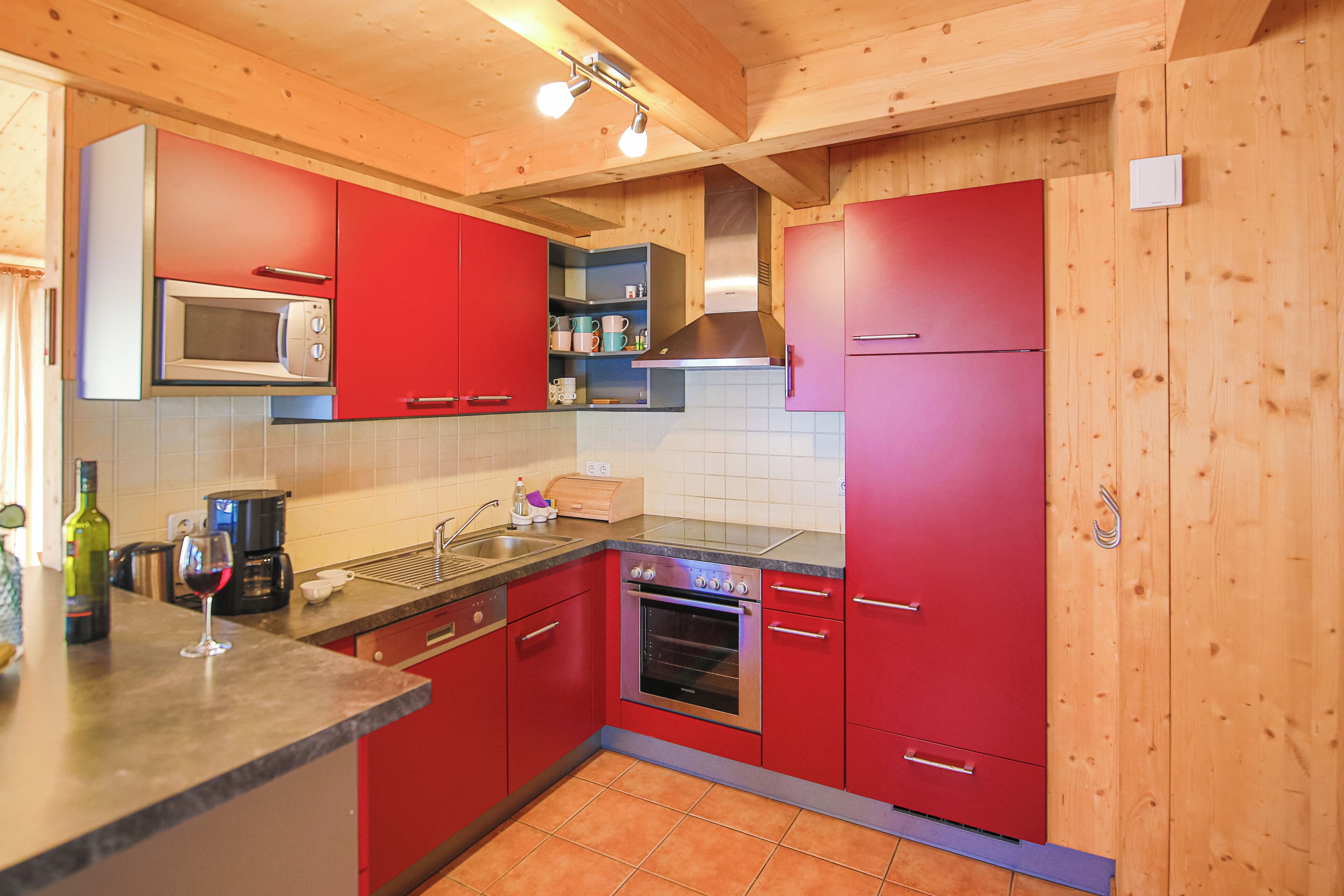 A kitchen with red cabinets, a microwave, a stove, and a sink.