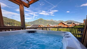 A hot tub with a view of mountains and wooden cabins. - Almdorf Hohentauern by ALPS RESORTS (Hohentauern)