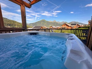 Un bain à remous avec vue sur les montagnes et des chalets en bois.
