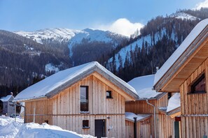 Une cabane en bois, dont le toit est recouvert de neige, nichée au cœur d’un paysage montagneux.