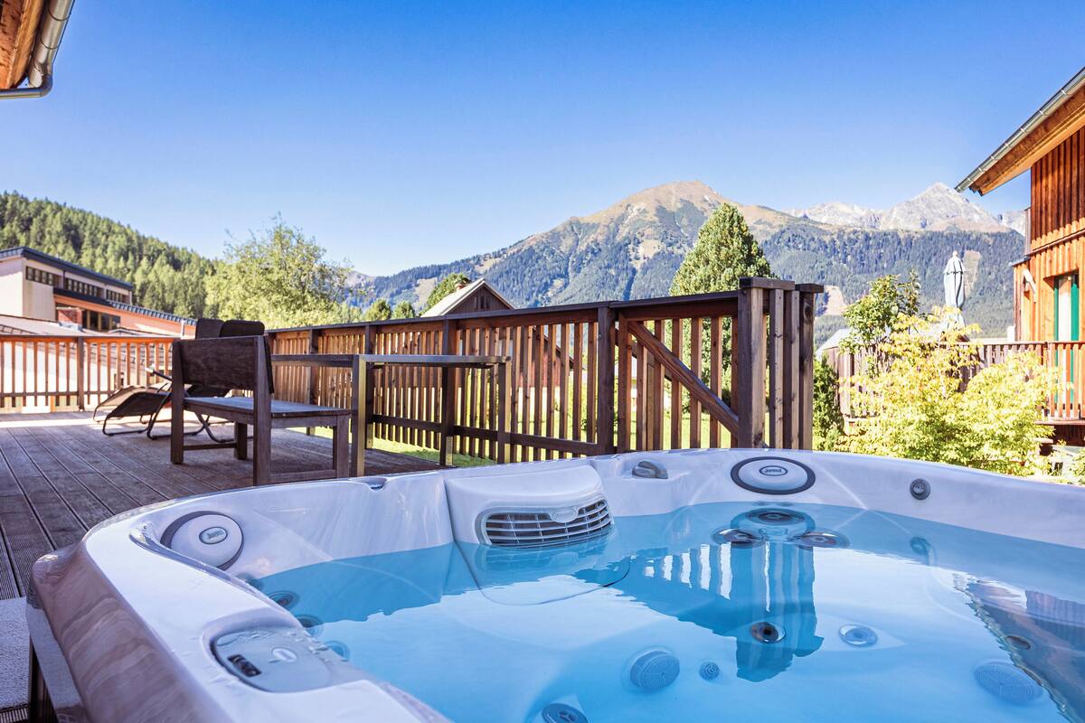 Un jacuzzi en una terraza de madera con vista a la montaña.