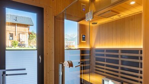 Eine Sauna mit Holzwänden, einer Glastür und Blick auf ein Gebäude.
