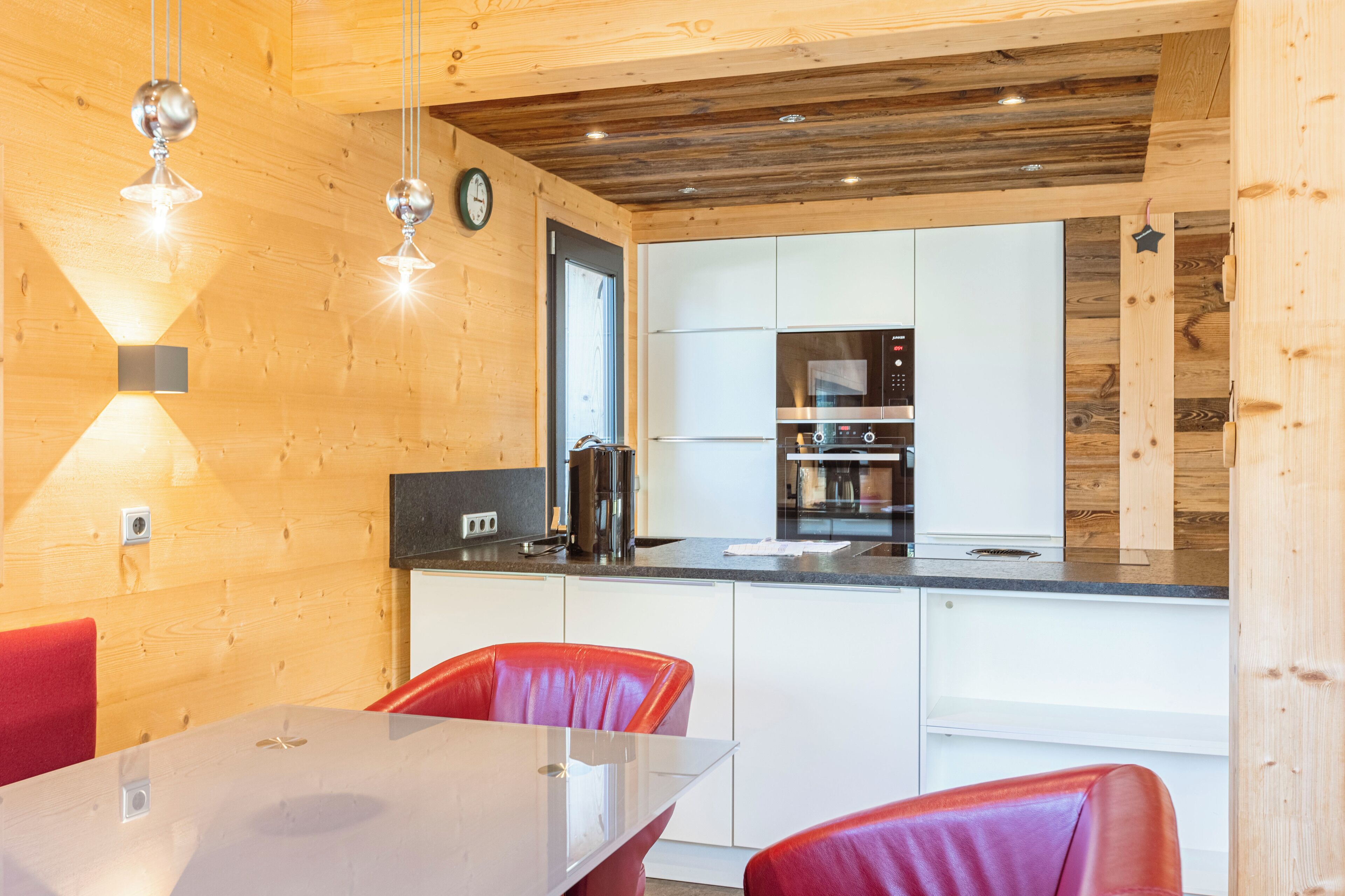 A modern kitchen with white cabinets, stainless steel appliances, and a wooden ceiling.