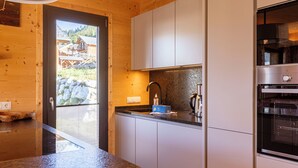 Eine moderne Küche mit Holzwänden, einer Granitarbeitsplatte, weißen Schränken und einem eingebauten Backofen.