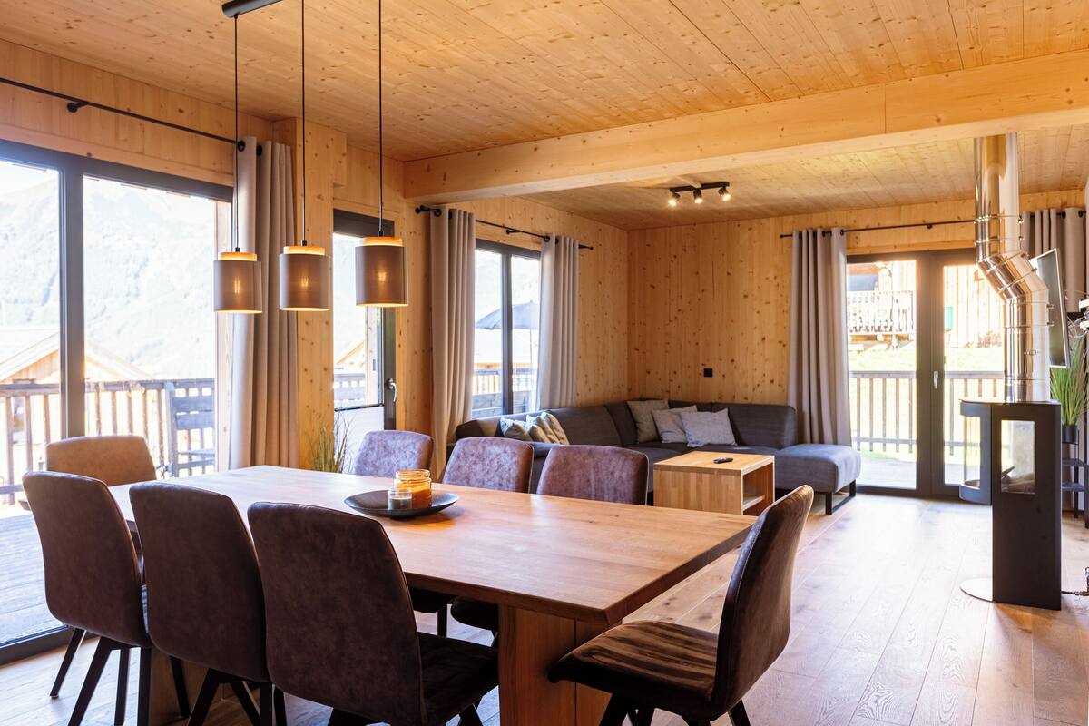 Un interior de madera con una mesa de comedor, sillas, un sofá y una chimenea.