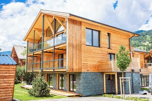 A modern wooden house with a balcony, large windows, and a stone foundation. - Kreischberg Pool Villas & Penthouses by ALPS RESORTS (Sankt Georgen am Kreischberg)