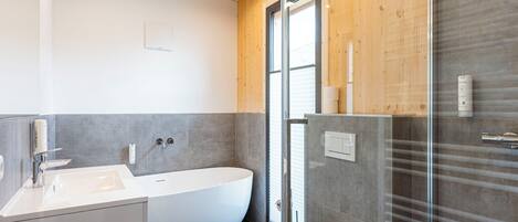 A modern bathroom with a freestanding bathtub, a toilet, and a glass-enclosed shower area.