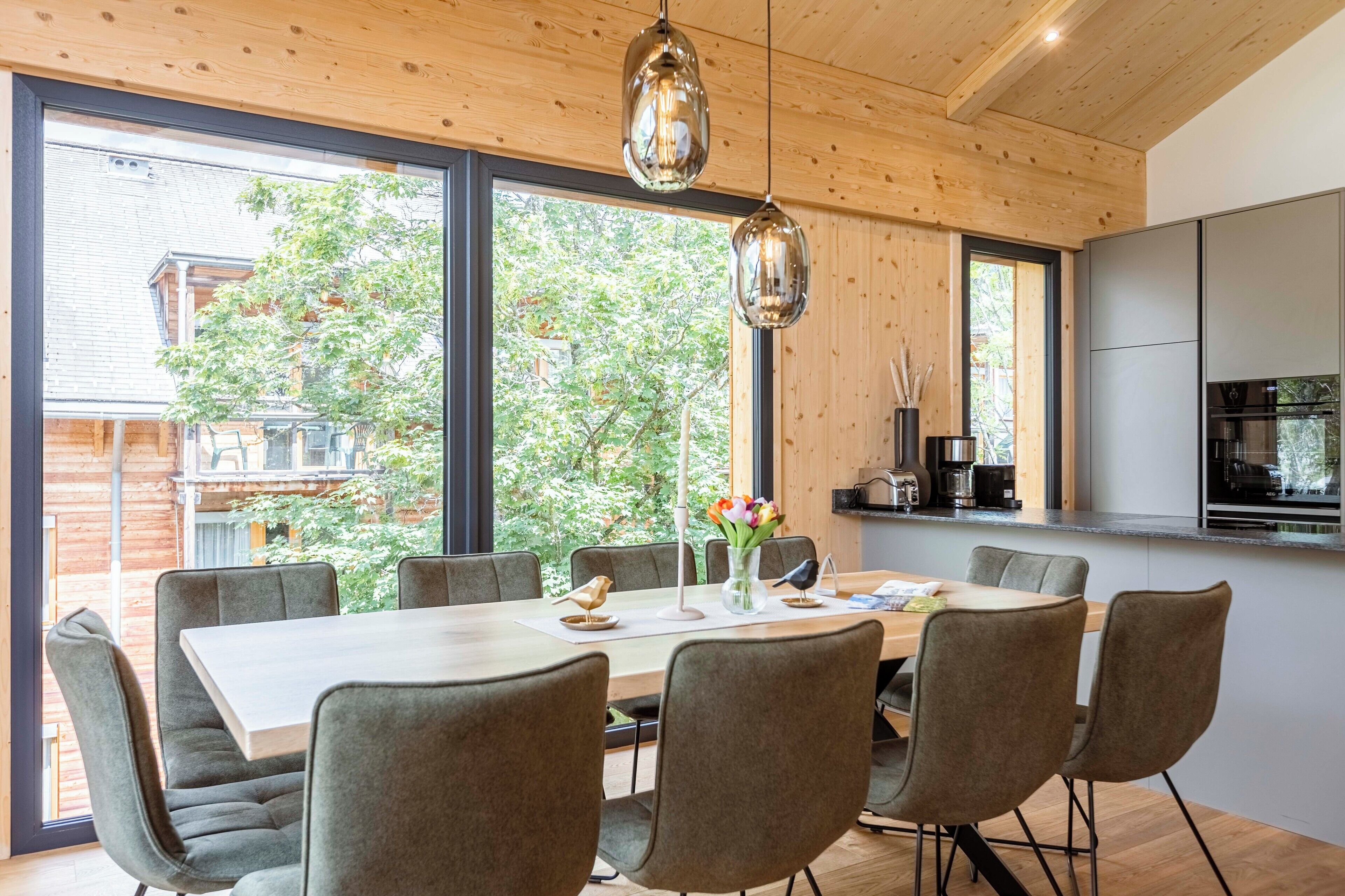 Un'area pranzo moderna con un tavolo grande, sei sedie e due lampadari a sospensione.