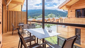 A wooden cabin with a balcony, a dining table, and chairs.