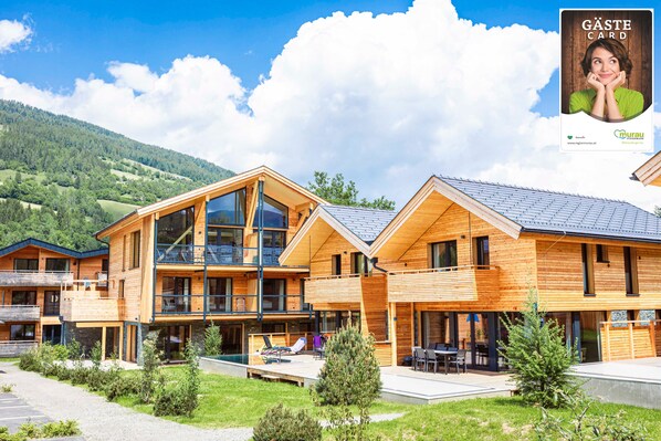 A modern wooden building with a pool, outdoor seating, and a mountainous backdrop. - Kreischberg Pool Villas & Penthouses by ALPS RESORTS (Sankt Georgen am Kreischberg)