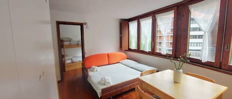 A compact room with a bunk bed, a small desk, and a window with curtains.