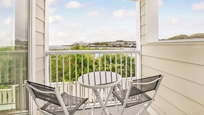 A balcony with a table and two chairs, overlooking a coastal view with houses and greenery. - Sands Beach Club #112 (Myrtle Beach)