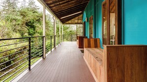 Una terraza de madera con barandilla, bancos de madera y un área cubierta con techo de madera.