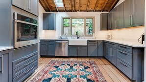 Una cocina moderna con gabinetes grises, electrodomésticos de acero inoxidable y techo de madera.