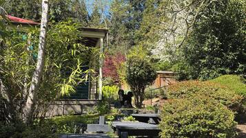 A garden with picnic tables and a building with a red roof.