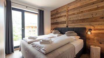 Ein modernes Hotelzimmer mit einem großen Bett, einer Wand aus Holzpaneelen und Blick ins Freie.