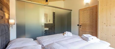A hotel room with a bed, a wooden ceiling, a sliding door, and a wall-mounted light fixture.