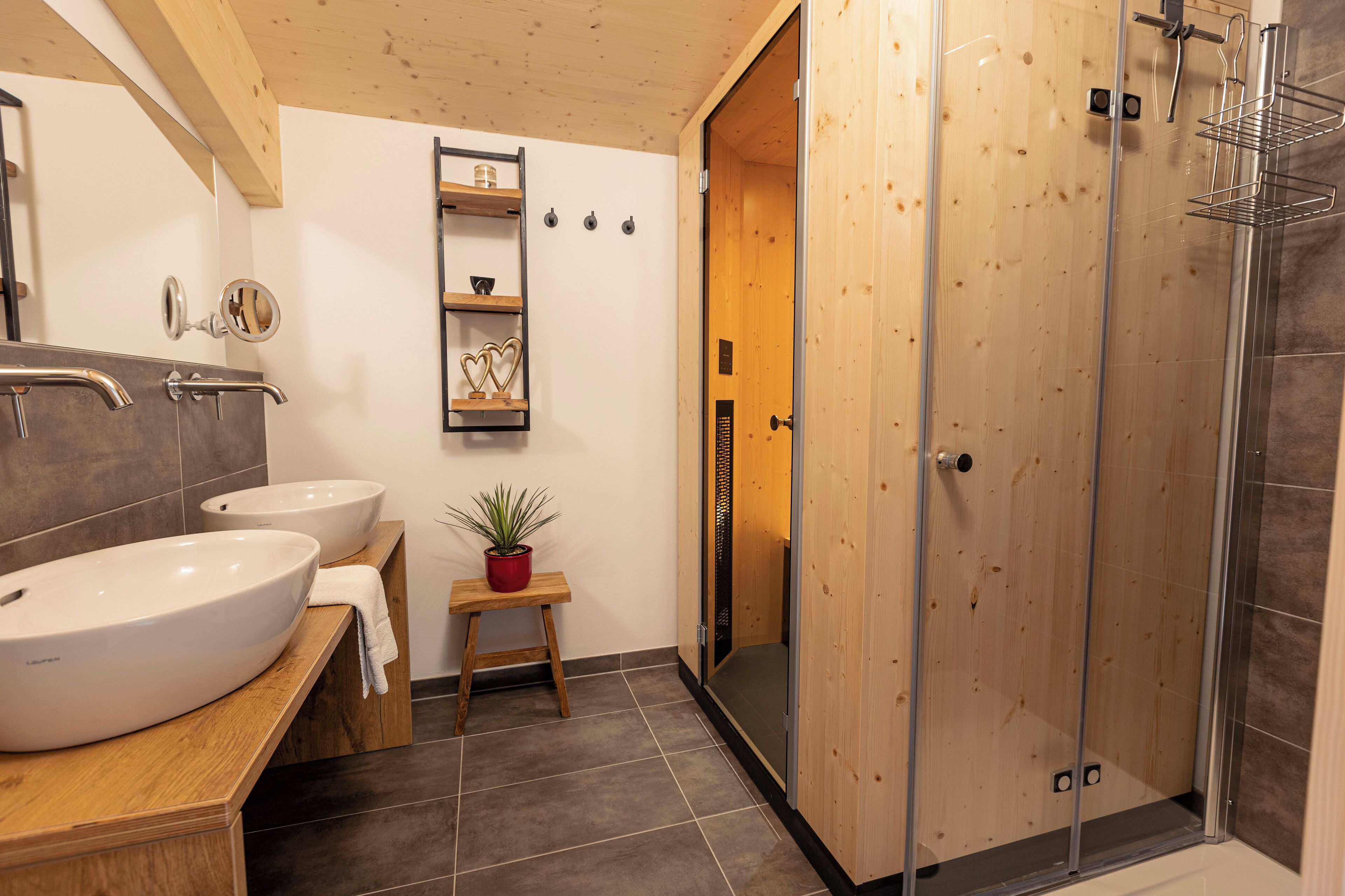 Un baño moderno con dos lavamanos, ducha y tocador de madera.