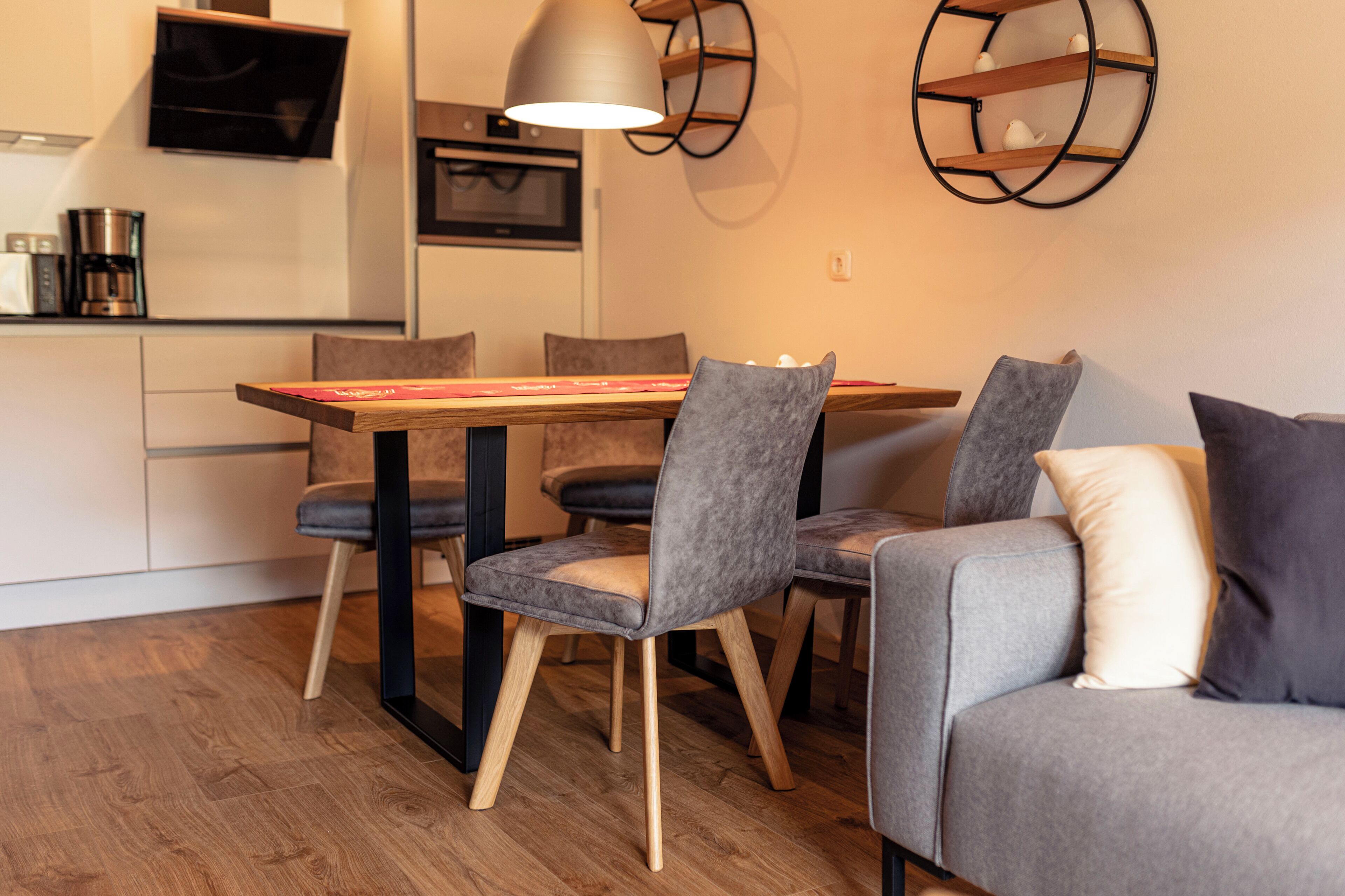 Une cuisine moderne avec une table et des chaises, un canapé et un téléviseur fixé au mur.