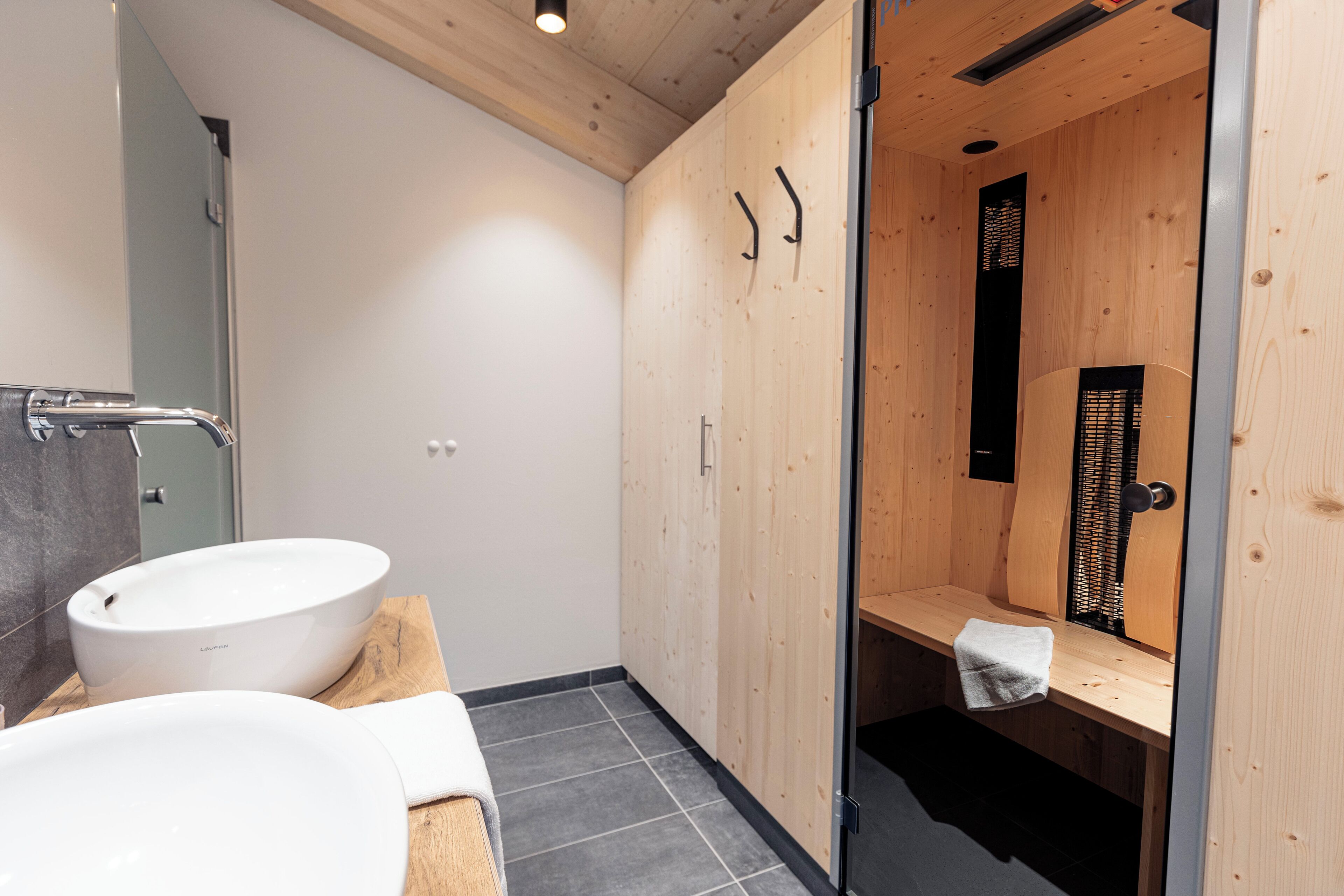 A modern bathroom with a wooden vanity, a large white sink, and a glass shower enclosure.