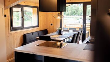 Una cocina moderna con una isla central, paredes de madera y ventanas grandes.