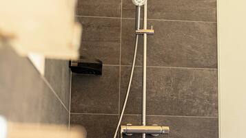 A shower with a handheld showerhead and a wall-mounted control panel.