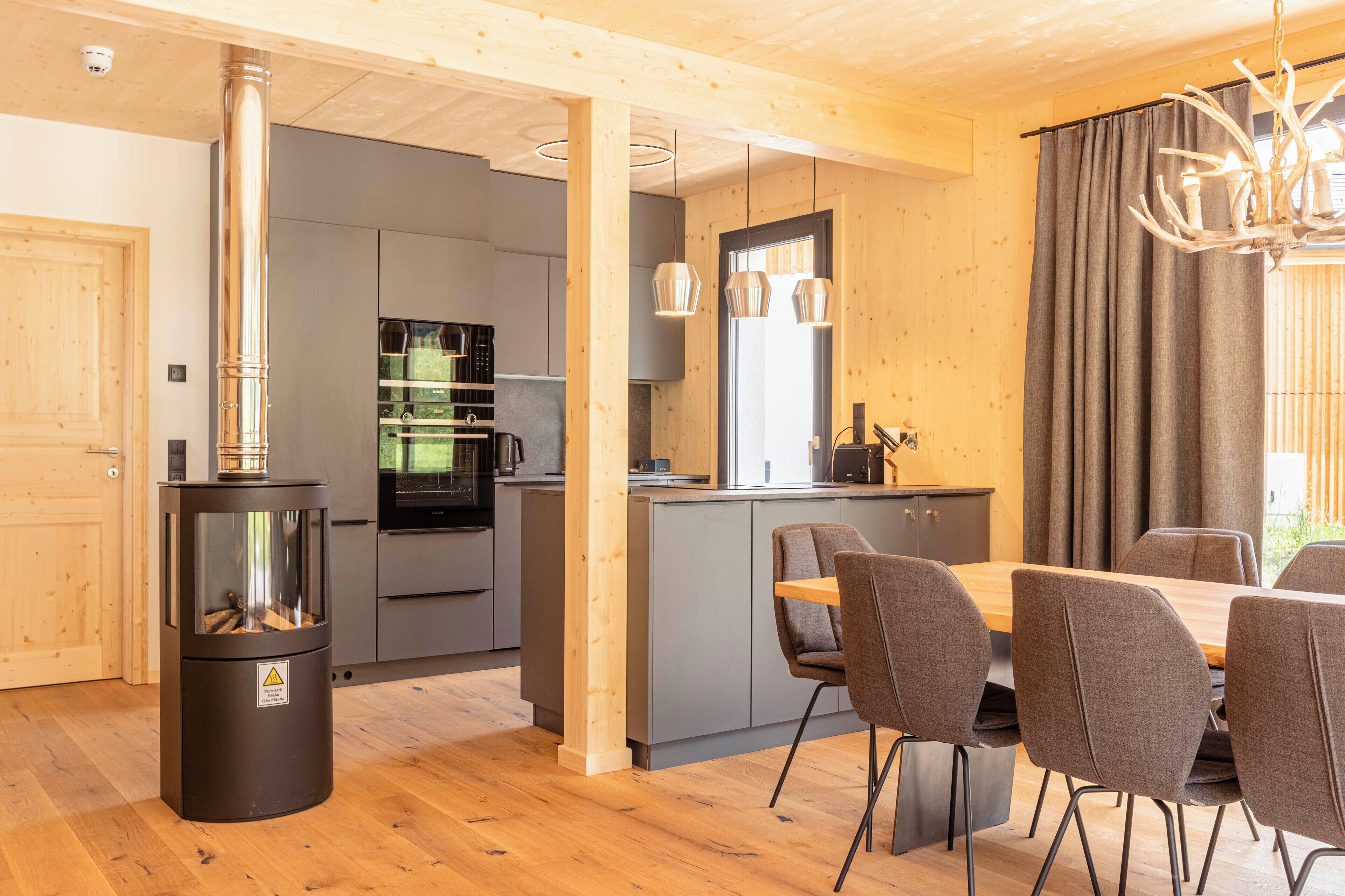 Una cucina moderna con mobili grigi, un'isola centrale e un'area pranzo con tavolo e sedie in legno.