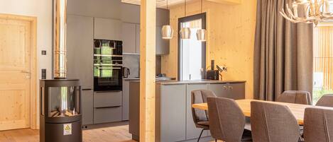 Una cucina moderna con mobili grigi, un'isola centrale e un'area pranzo con tavolo e sedie in legno.