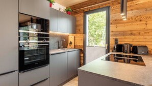 A modern kitchen with stainless steel appliances, grey cabinets, and a wooden interior. - Alpenchalets Biberwier by ALPS RESORTS (Biberwier)