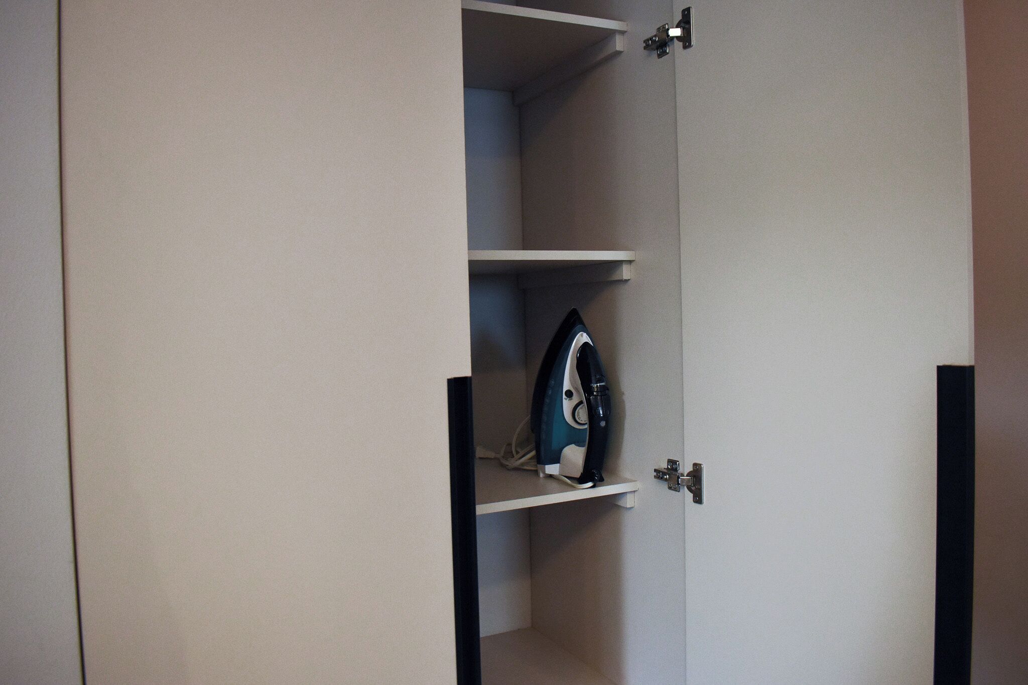 Een kast met een hangend strijkijzer op een plank.