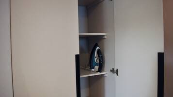 Een kast met een hangend strijkijzer op een plank.