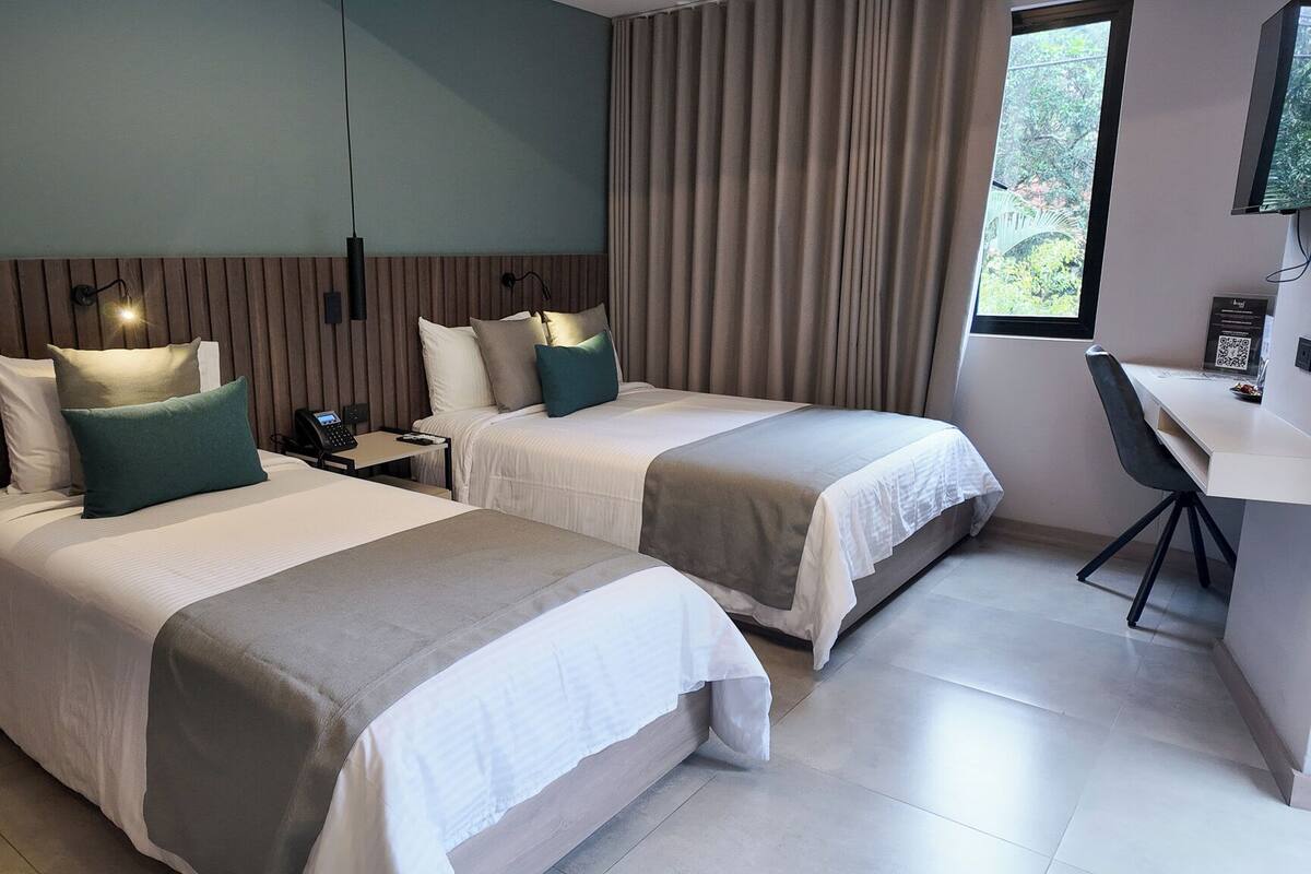 Een hotelkamer met twee bedden, een bureau en een stoel.