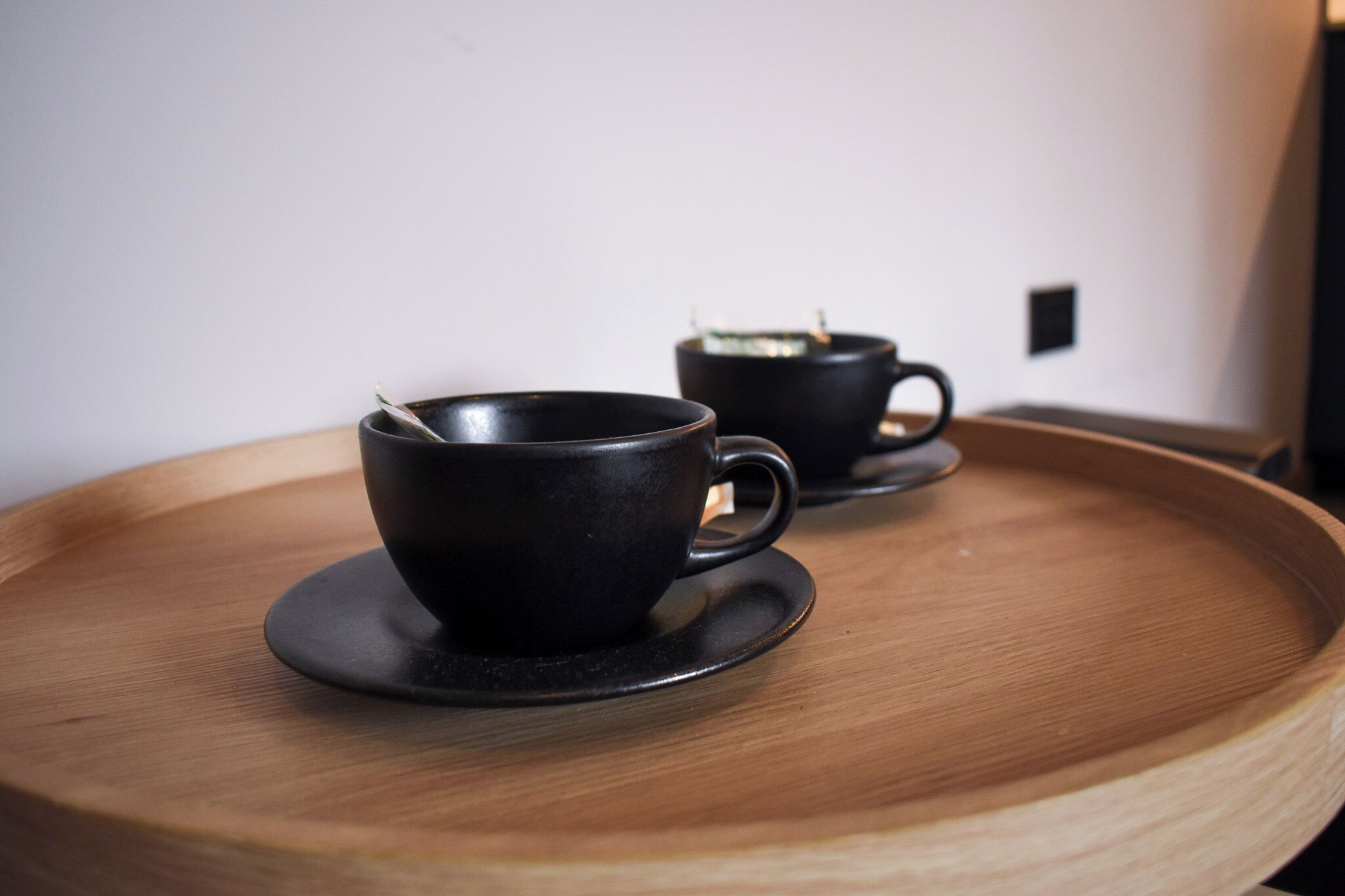 Dos tazas negras sobre una bandeja de madera.